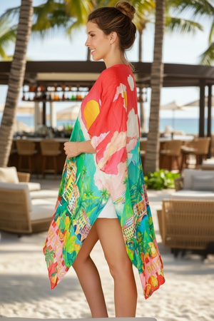 Woman wearing a colorful floral kimono on a beach with palm trees and a restaurant in the background.