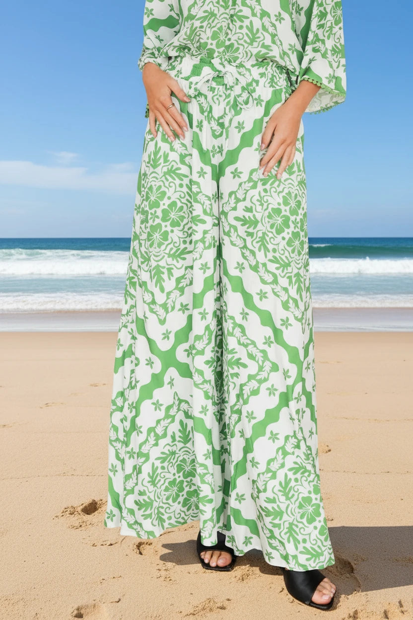 Person wearing a green and white floral dress on a beach