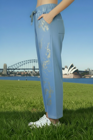 Person wearing blue pants with gold paint patterns on the front. 