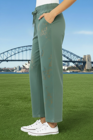 Person wearing green pants with gold paint on the front of the pant legs