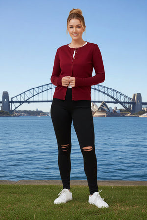 Woman in red cardigan and black leggings standing in front of the Sydney Harbour Bridge.