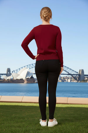 Person wearing a red sweater and black leggings standing on grass with the Sydney Opera House and Harbour Bridge in the background.