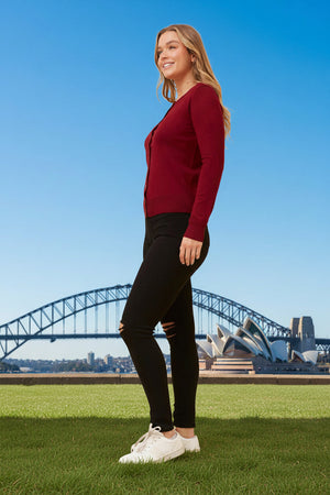 Woman in a red sweater and black pants standing on grass with the Sydney Harbour Bridge in the background