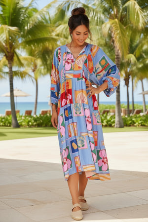 Woman in a colorful dress standing on a tropical beach with palm trees in the background.