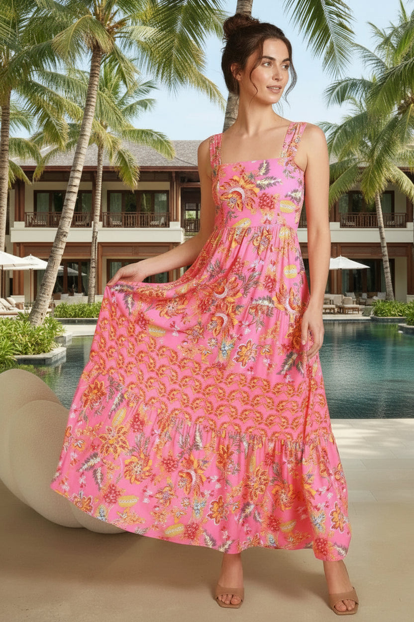 Woman wearing a pink floral dress in a room with beige walls and a vase of dried flowers.