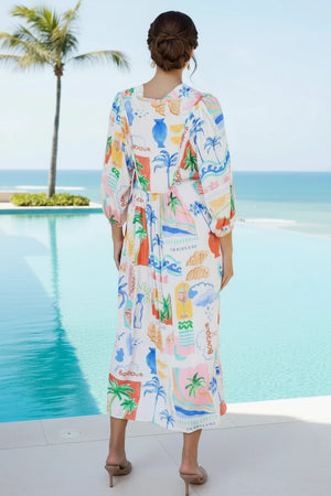 Woman wearing a colorful dress with palm tree patterns by a pool with a palm tree in the background.