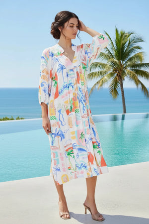 Woman in a colorful dress standing by a pool with palm trees and ocean view