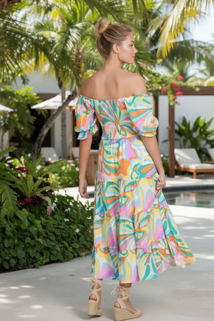 Woman in a colorful dress standing by a pool with palm trees in the background