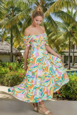 Woman in a colorful off-shoulder dress standing in a tropical setting with palm trees.