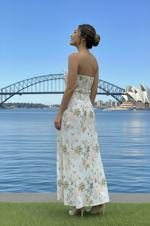 Woman in a floral dress standing by the water with a bridge and Opera House in the background