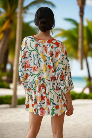 Woman wearing a colorful floral dress on a beach with palm trees in the background