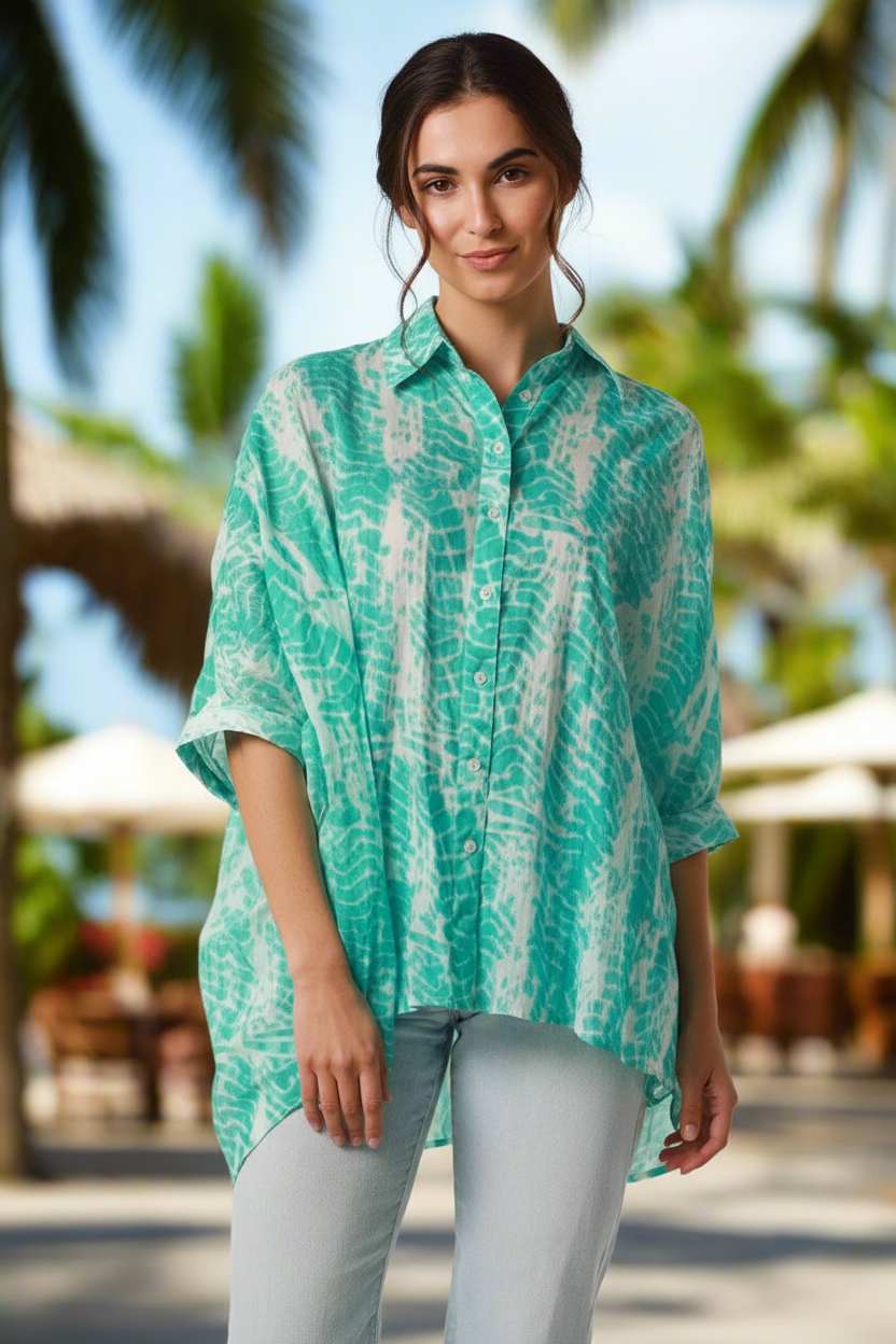 Woman wearing a green and white patterned top with a blurred outdoor background