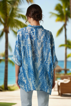 Woman wearing a blue and white patterned kimono with palm trees and ocean in the background