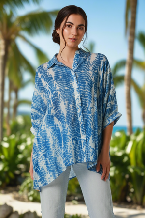 Woman wearing a blue and white patterned shirt with palm trees in the background