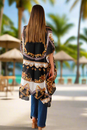 Woman wearing a patterned kimono-style garment on a beach with palm trees in the background