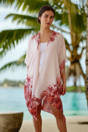 Woman wearing a floral cover-up by a palm tree with a beach background