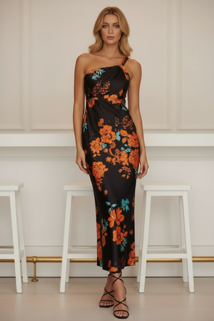 Woman wearing a black floral dress standing in a minimalistic room with white stools.