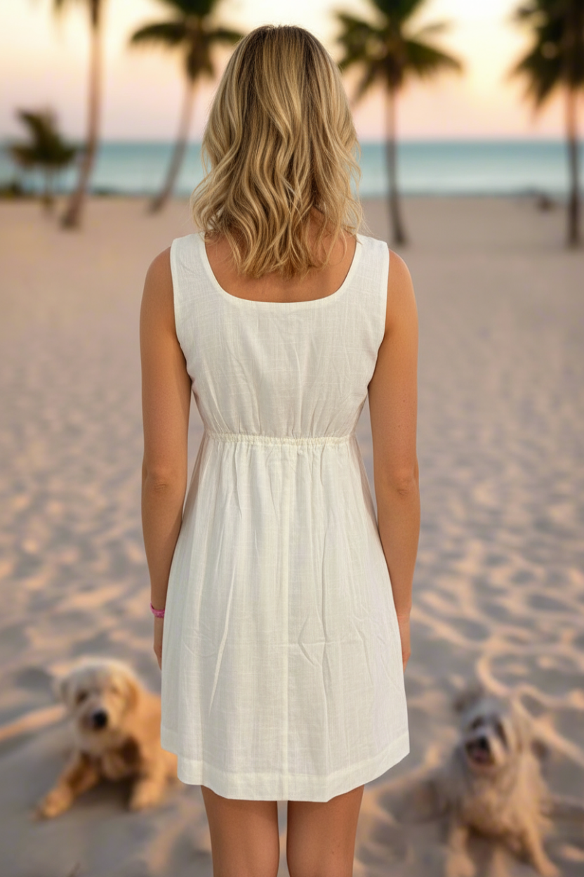 Woman in a white dress standing on a beach with palm trees and sunset in the background
