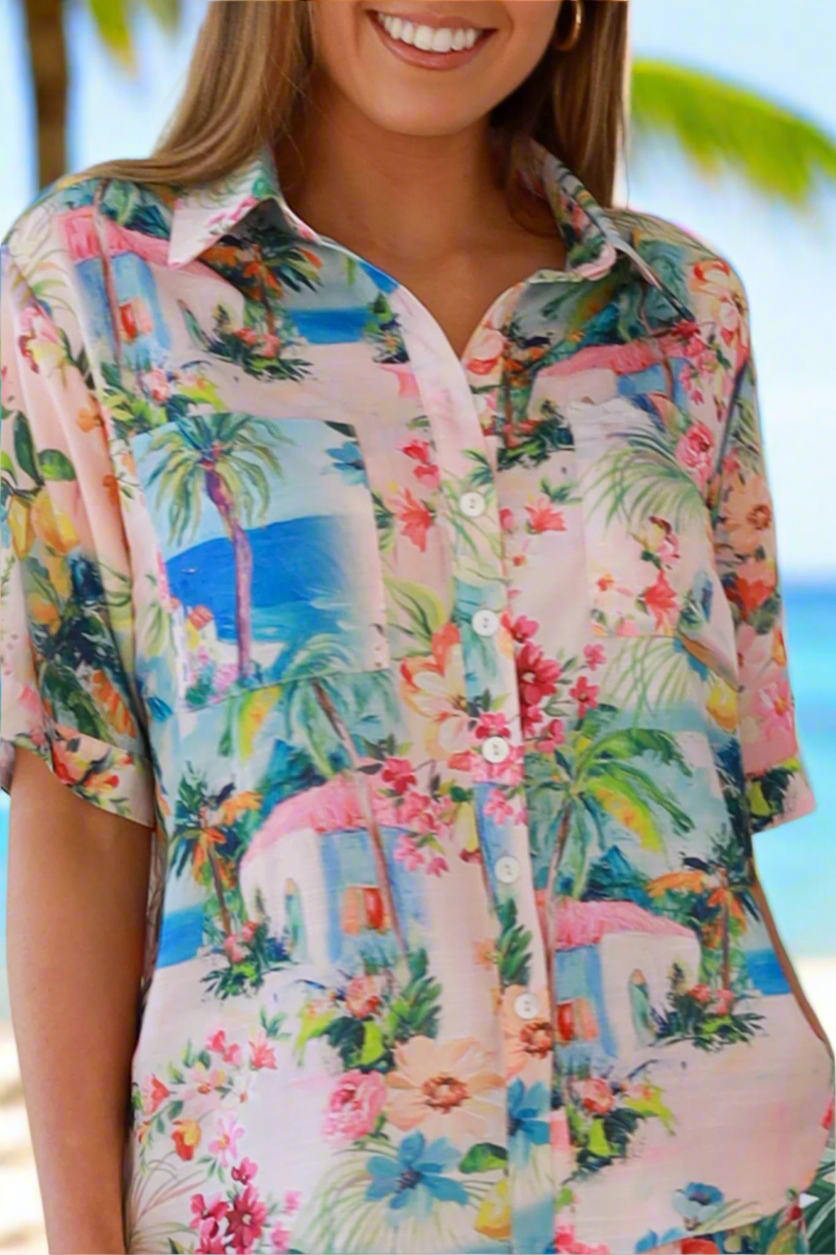 Woman wearing a colorful tropical print shirt on a beach.
