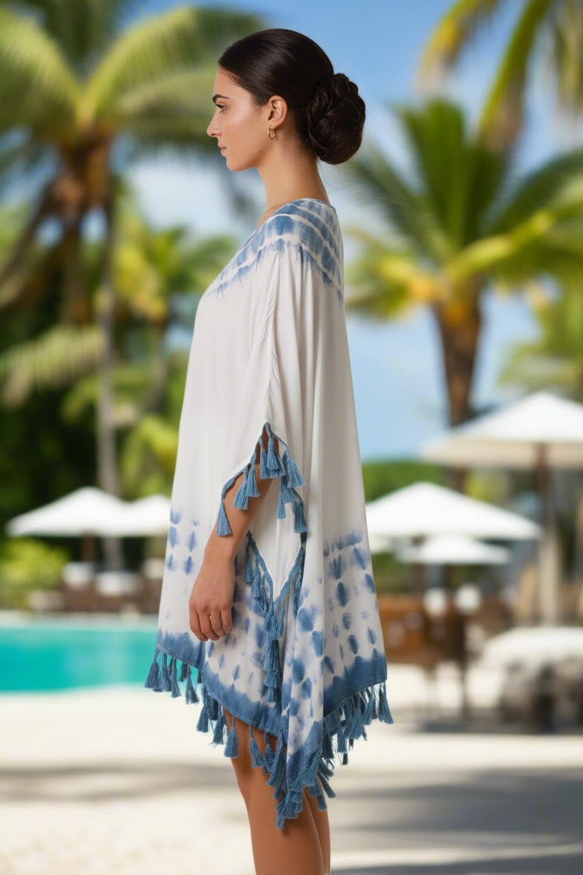 Woman wearing a white and blue patterned cover-up by a pool with palm trees in the background