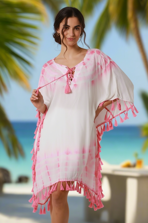 Woman wearing a pink and white dress with tassels on a beach