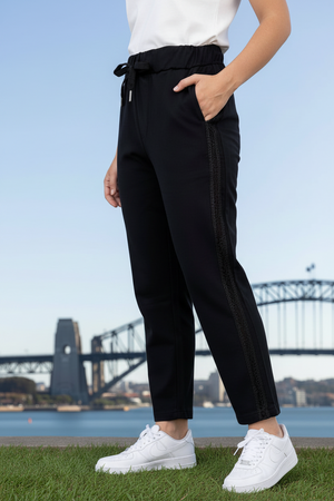 Person wearing drawer string black pants with vertical sequins stripes on the side