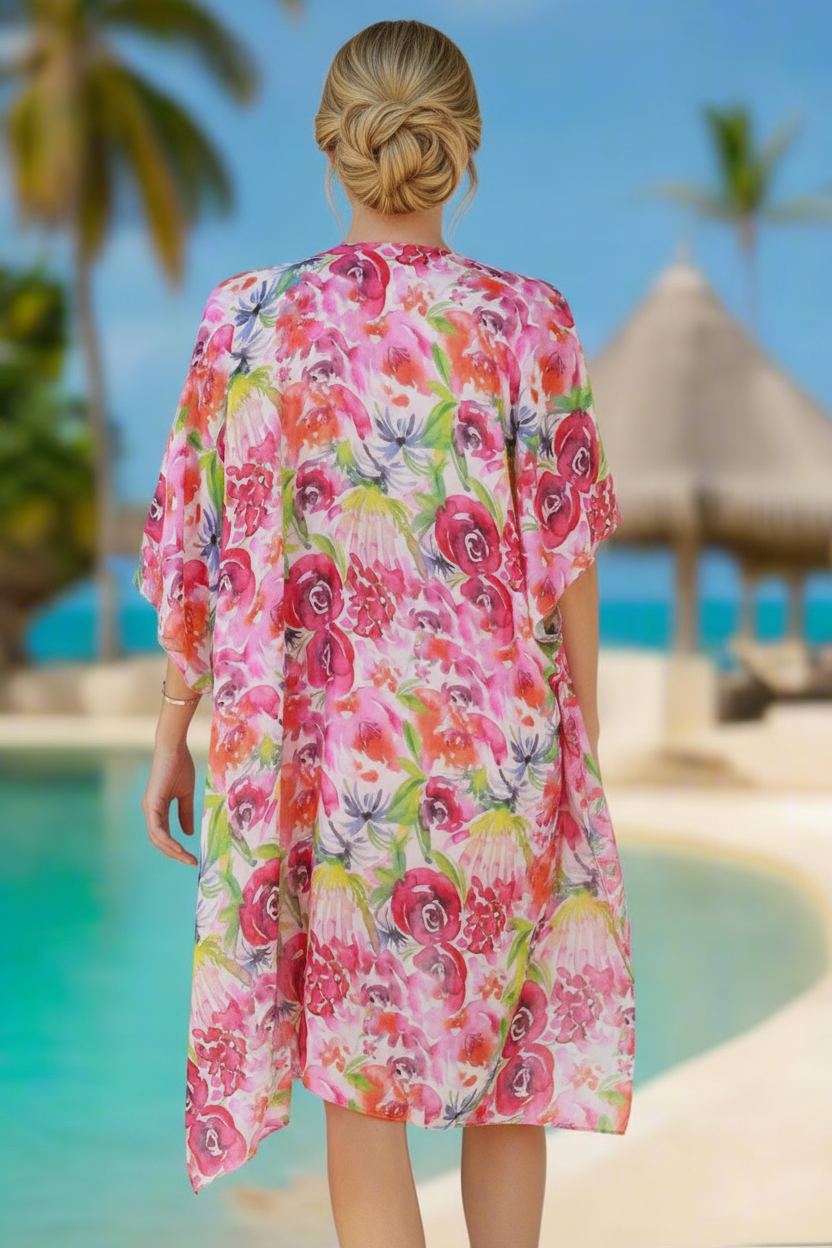 Woman wearing a colorful floral dress by a pool with palm trees and a hut in the background.