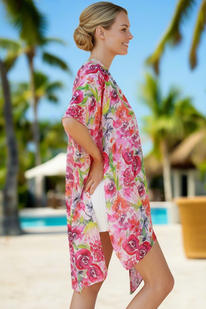 Woman wearing a colorful floral cover-up in a tropical setting with palm trees and a pool.