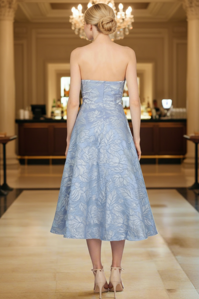 Woman wearing a light blue strapless lace dress in an elegant indoor setting.