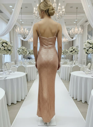 Woman in a sparkly evening gown walking down a decorated hallway with white tables and floral arrangements.