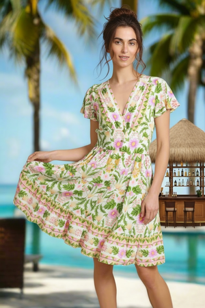 Woman in a floral dress standing by a pool with palm trees in the background