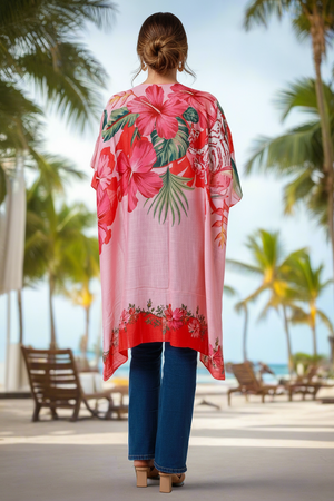 Woman wearing a pink floral kimono at a beach with palm trees in the background