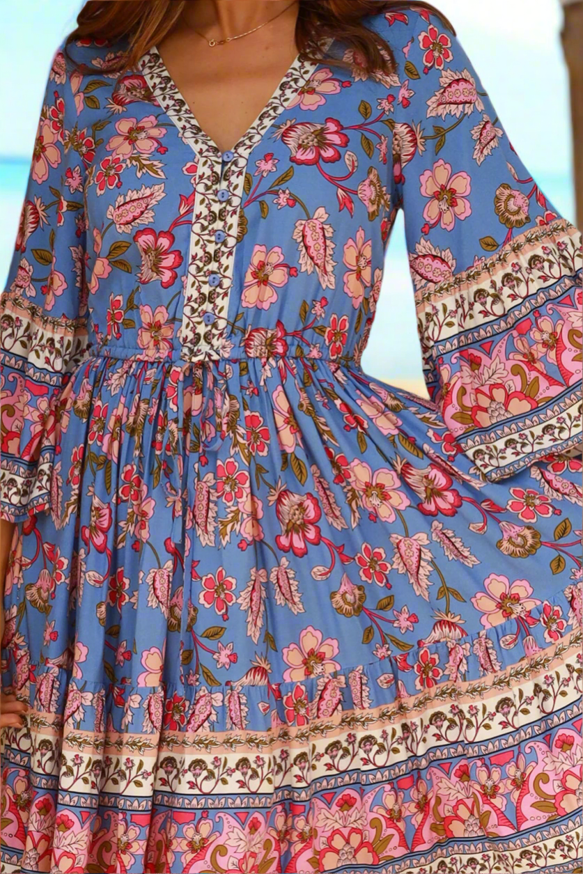 Blue floral dress with long sleeves and intricate patterns on a blurred background