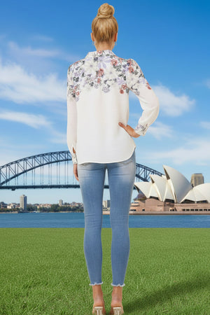 Back view of woman wearing a white floral blouse with jeans