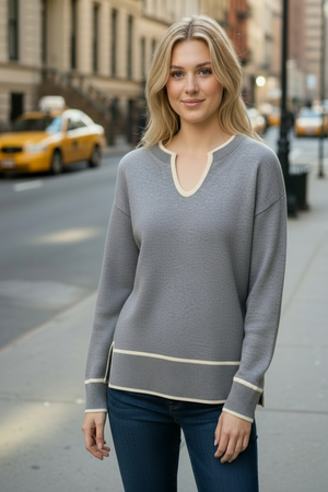 Woman wearing a gray sweater with a city street and taxi in the background