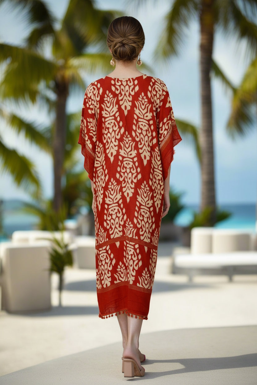 Woman in a red and white patterned dress walking on a beach with palm trees in the background