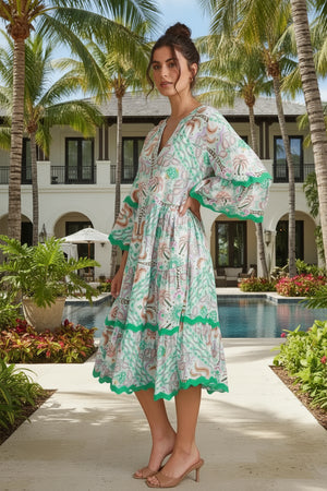 Woman in a floral dress standing in a tropical setting with palm trees and a pool.