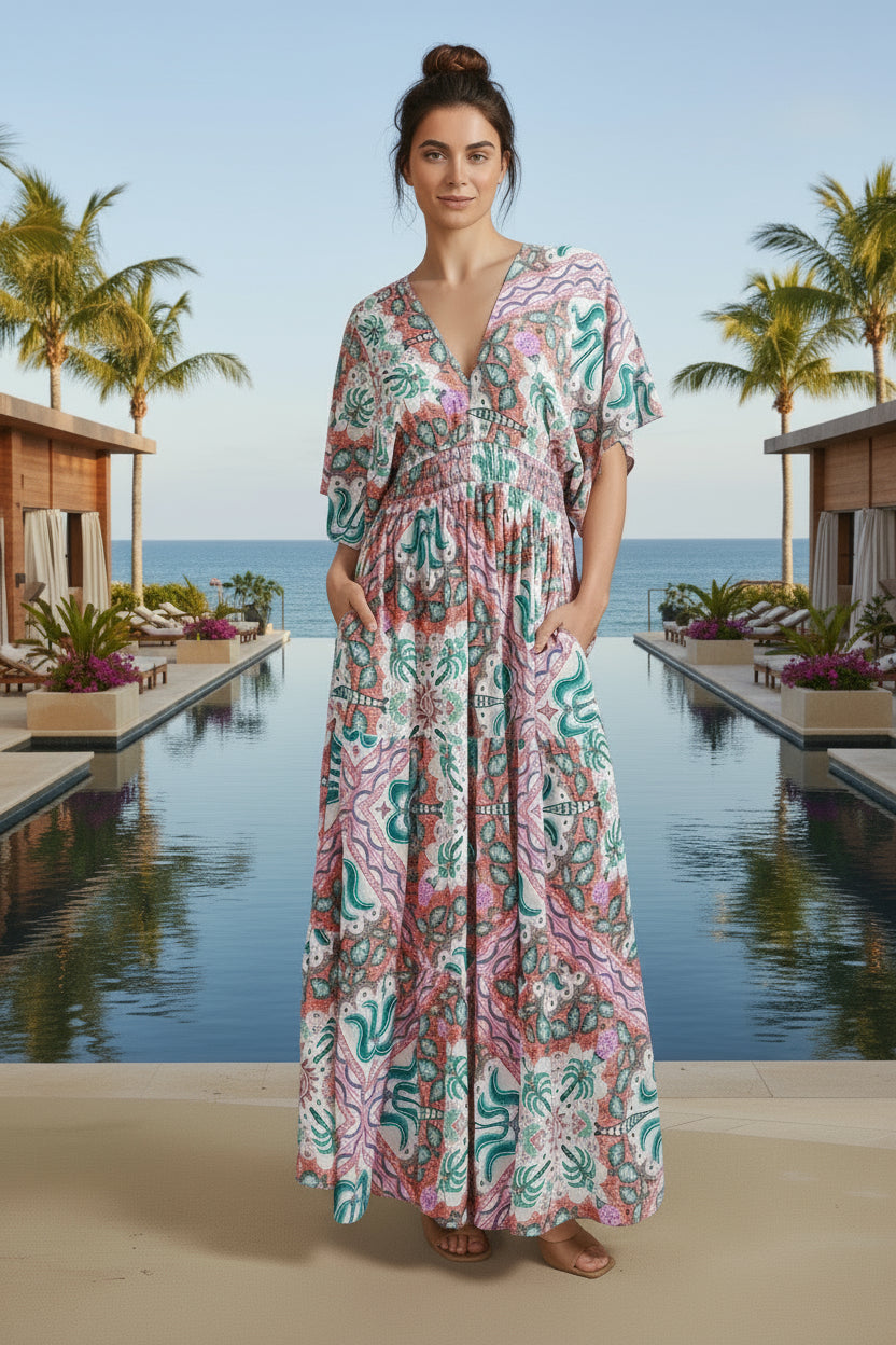 Woman wearing a colorful patterned dress standing outdoors with palm trees and a building in the background.
