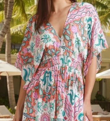 Woman wearing a colorful patterned dress against a neutral background