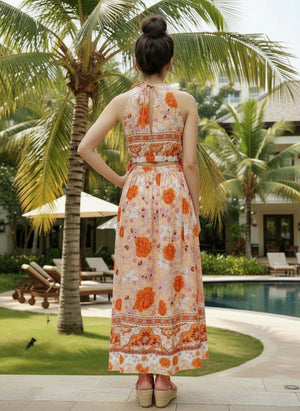 Woman in a floral dress standing by a pool with palm trees in the background