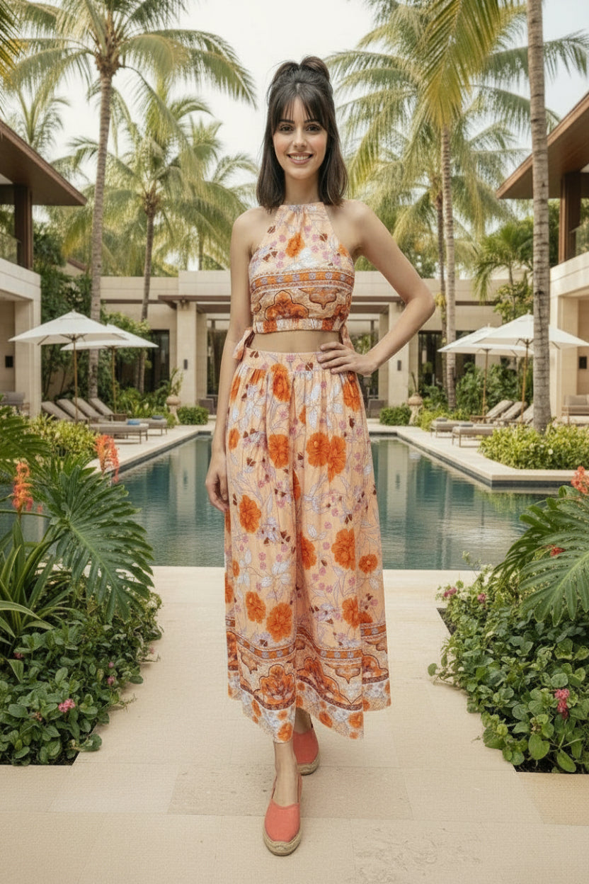 Woman in a floral dress standing in a tropical setting with palm trees and a pool.