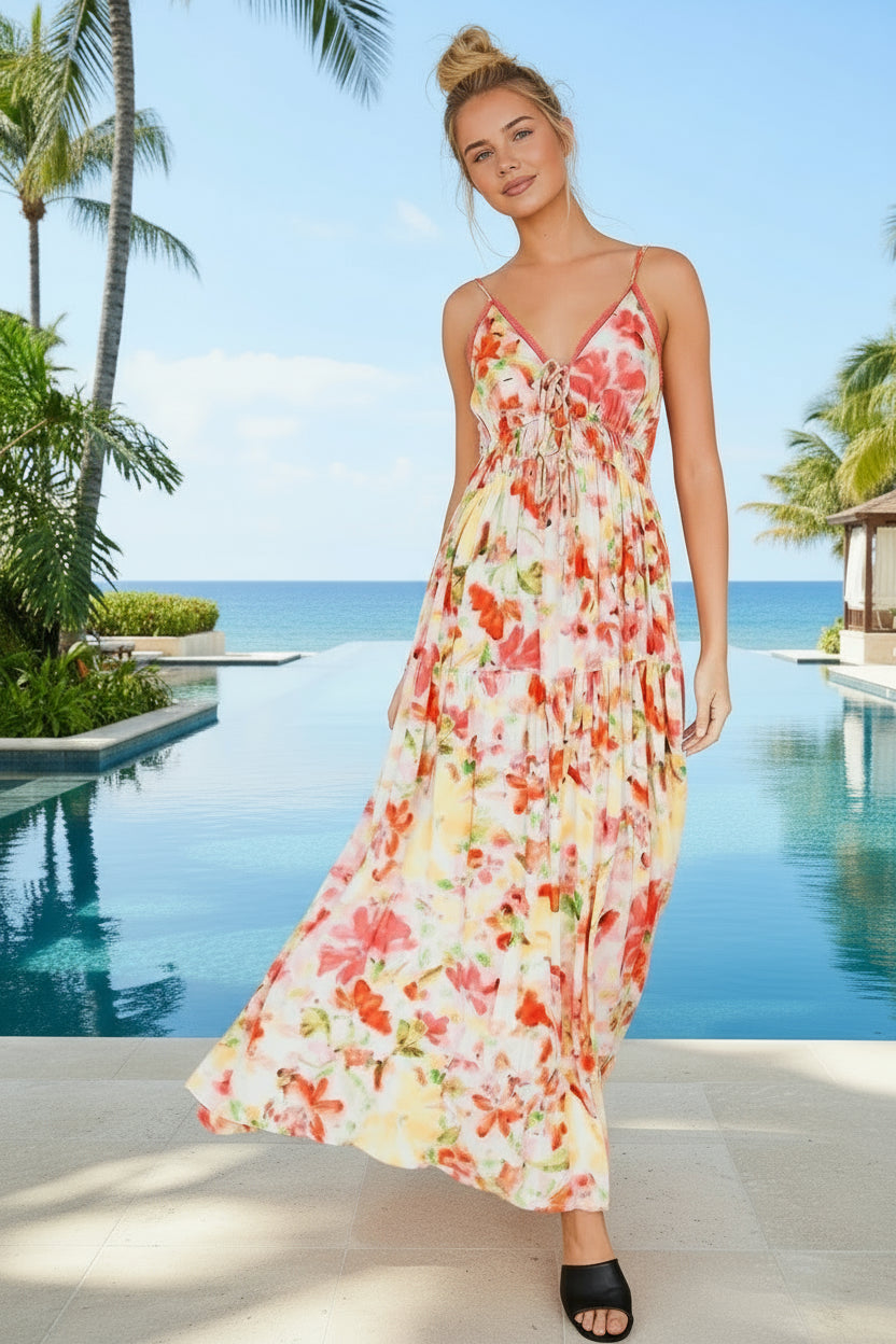 Woman in a floral dress standing by a pool with palm trees in the background