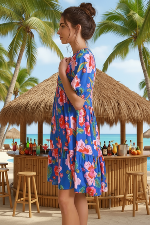 Woman in a floral dress standing in front of a beach bar with palm trees in the background