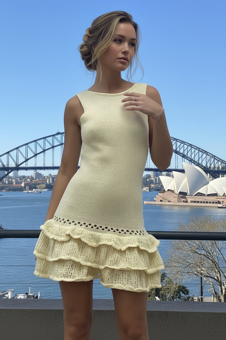 Woman in a yellow knit dress standing in front of the Sydney Harbour Bridge and Opera House.
