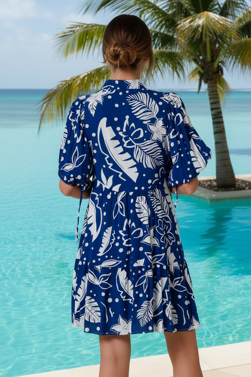 Woman wearing a blue dress with white floral pattern on a plain background