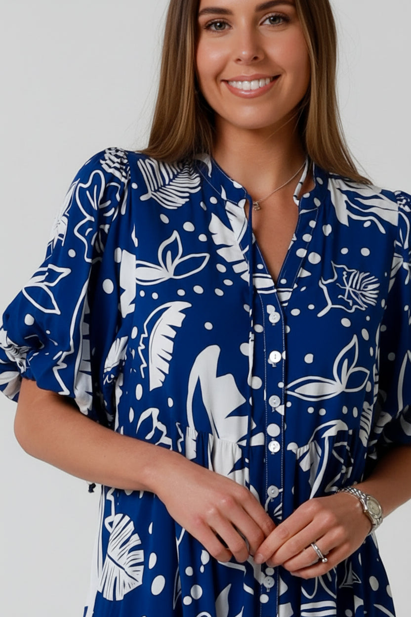 Woman wearing a blue dress with white floral patterns on a plain background