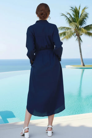 Woman in a blue dress standing by a pool with palm trees and ocean view