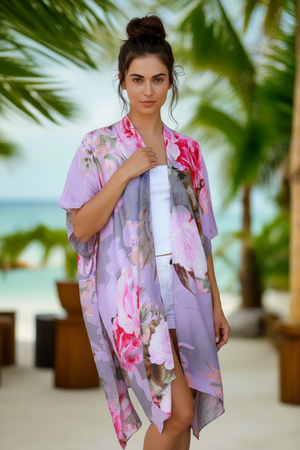 Woman wearing a floral kimono-style garment with palm trees and beach in the background