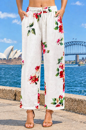 White cotton cropped pants with a red and green floral print, featuring an elastic drawstring waist and side pockets