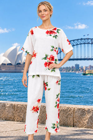 A cotton two-piece set featuring a short-sleeve top and matching capri pants in a greyish white with a red and green floral print